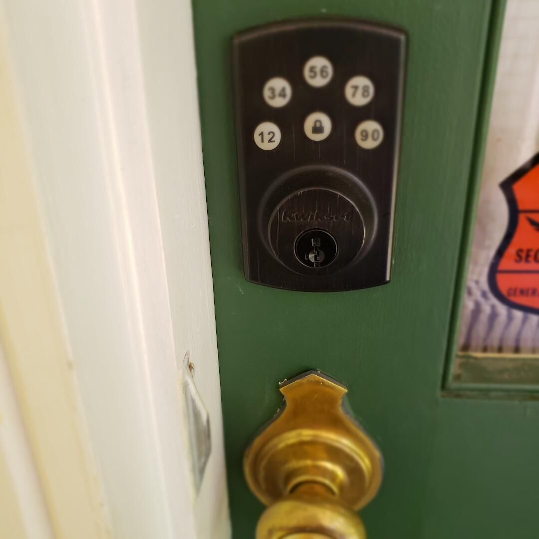 Una puerta con teclado electrónico y picaporte de latón.