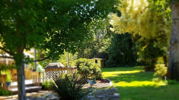 Ein Garten mit einer Holzterrasse, einem kleinen Schuppen und einem Kiesweg.
