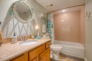 A bathroom with a sink, mirror, toilet, and bathtub.