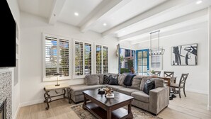 A modern living room with a sectional sofa, a coffee table, and a dining area with a table and chairs. - Newly Renovated Luxurious Villa with Fountain View, Pet Friendly! - Ground Floor (T21) (La Quinta)