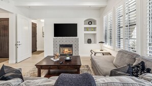 A modern living room with a fireplace, a sofa, a coffee table, and a television. - Newly Renovated Luxurious Villa with Fountain View, Pet Friendly! - Ground Floor (T21) (La Quinta)