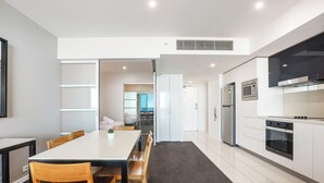 A modern kitchen with white cabinets, a stainless steel oven, and a microwave. - TOP FLOOR H Residence 13204 - Level 32 2 bedrooms (Surfers Paradise)