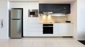 A modern kitchen with white cabinetry, stainless steel appliances, and a black oven. - TOP FLOOR H Residence 13204 - Level 32 2 bedrooms (Surfers Paradise)
