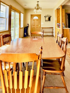Un comedor con una gran mesa de madera, sillas y una lámpara de araña.