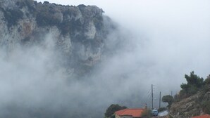 A mountainous landscape with a building with a red roof.