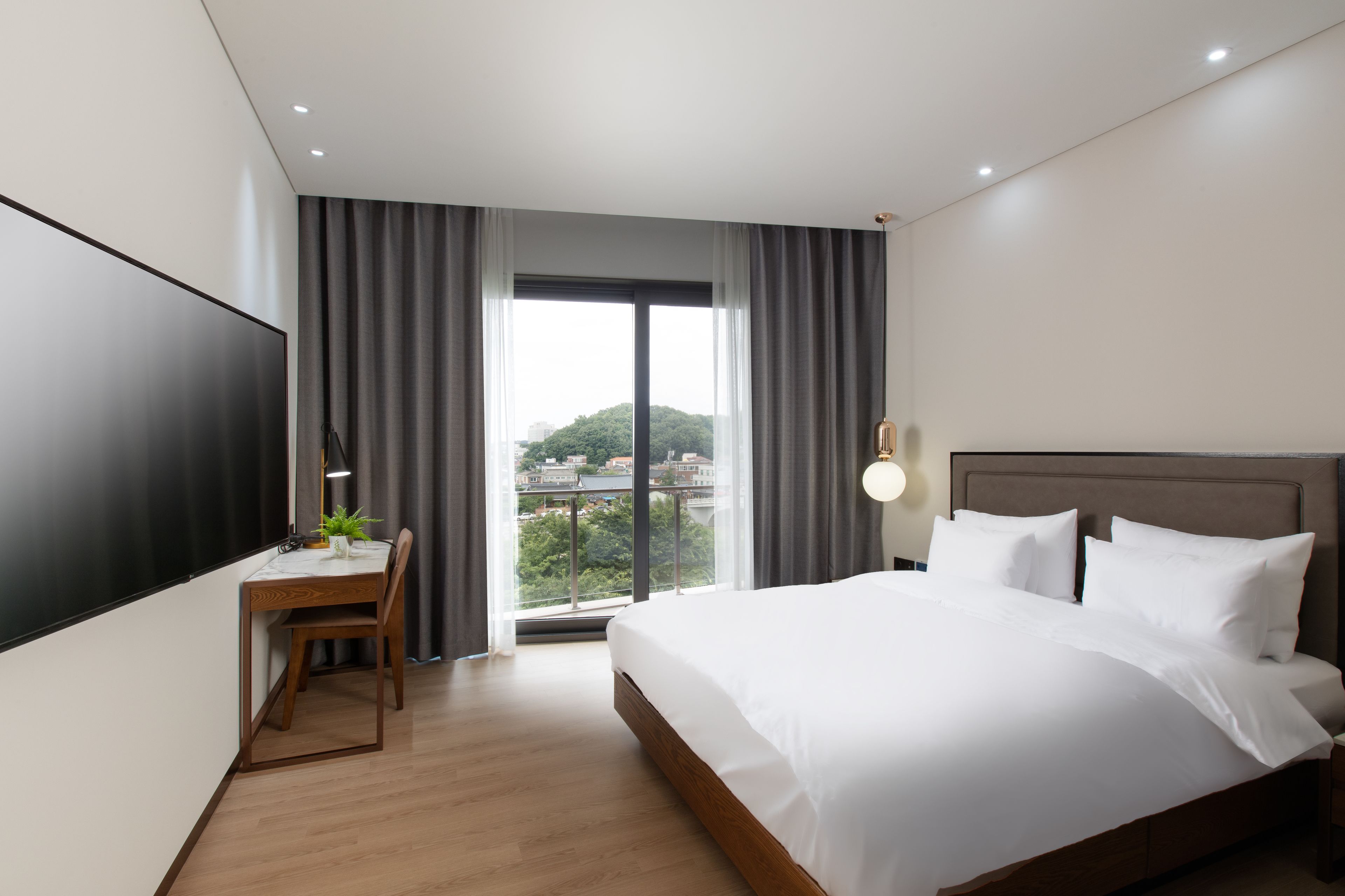 Una habitación de hotel moderna con una cama grande, un escritorio y vistas de la ciudad a través de la ventana.