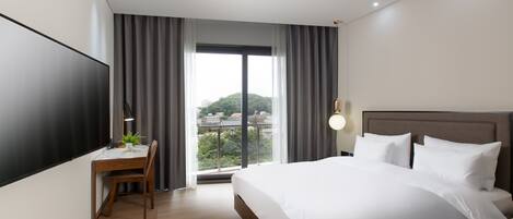 Una habitación de hotel moderna con una cama grande, un escritorio y vistas de la ciudad a través de la ventana.