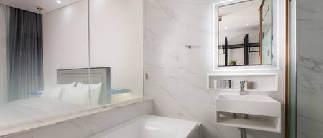Un baño moderno con una bañera grande, cabina de ducha de vidrio y tocador blanco con espejo.