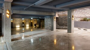 Un vaste espace de stationnement intérieur avec des piliers en béton, un sol poli et un mur en briques.