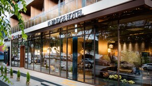 Un hôtel doté d’une façade en verre, d’une terrasse et d’un café visible de l’extérieur.
