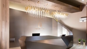 Un comptoir d’accueil moderne au design géométrique, un lustre et le logo de l’hôtel Bridge.