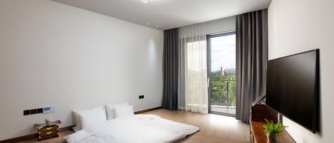 Una habitación de hotel moderna con una cama grande, un televisor de pantalla plana, un aparador de madera y vistas a la ciudad por la ventana.