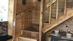 A wooden staircase leading to a loft area with a small table and chairs. - Experience Alaska with a touch of home! (Hollis)