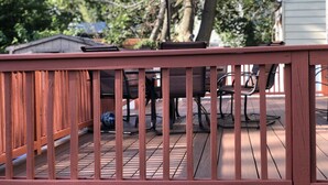 A wooden deck with a red umbrella, outdoor furniture, and a small shed in the background. - Charming One Family Colonial Home / Business . (East Orange)