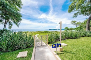 Stroll through the serene pathway to a lush oasis with ocean views and distant hills.