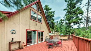 Une maison à deux étages avec une terrasse rouge, un coin repas aménagé avec du mobilier d’extérieur et une grande porte-fenêtre coulissante.