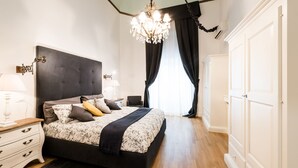Une chambre à coucher avec un grand lit, un lustre, une table de chevet et une armoire.