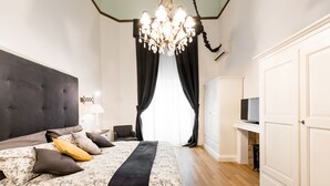 Une chambre à coucher avec un grand lit, un lustre, une télévision et une armoire.