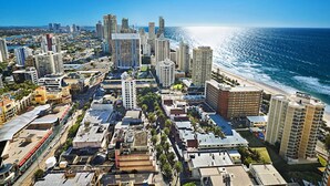 Un paysage urbain côtier avec de hauts immeubles, une plage et un ciel dégagé.