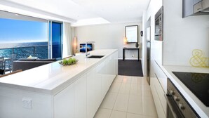 Une cuisine moderne dotée d’un grand îlot central, offrant une vue sur l’océan, et d’un coin repas avec vue.
