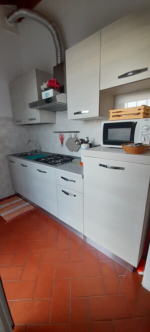 A compact kitchen with a gas stove, a microwave, and white cabinets.