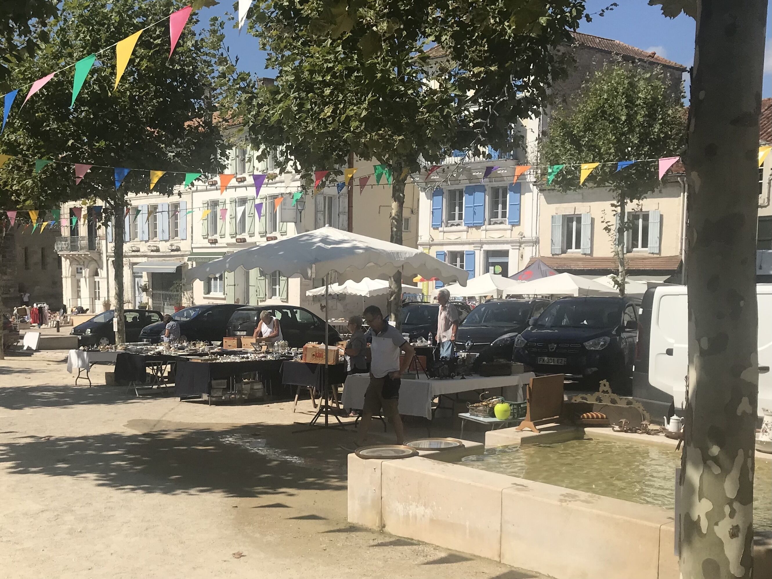 A street market with stalls and parked cars.