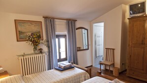 A bedroom with two beds, a radiator, a mirror, a television, and a wooden cabinet. - Villa Agriturismo Podere Pilar in Tuscany  10 people - spectacular swimming pool (Monsummano Terme)