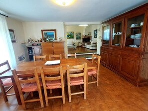 A dining area with a wooden table and chairs, a kitchen with cabinets, and a living area with a sofa and a fireplace. - Villa Agriturismo Podere Pilar in Tuscany  10 people - spectacular swimming pool (Monsummano Terme)