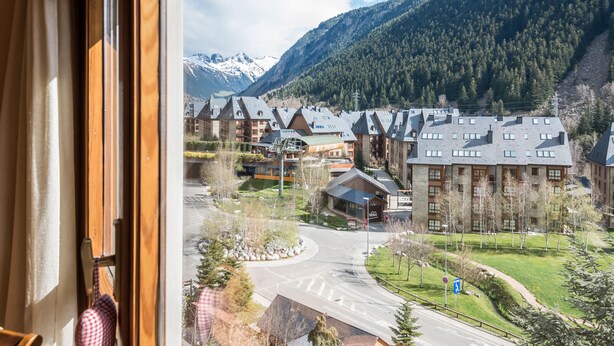Vista de un hotel con varias construcciones, una carretera y montañas al fondo.