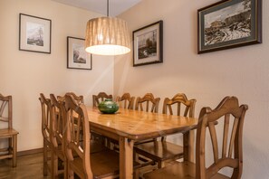 A dining room with a wooden table, chairs, and framed pictures on the wall.