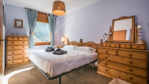Un dormitorio con cama, cómoda de madera y espejo.