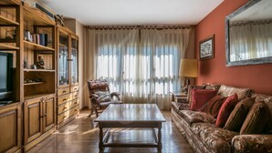 Una sala de estar con una mesa de centro de madera, un sofá, un sillón de cuero y un televisor sobre un mueble de madera.