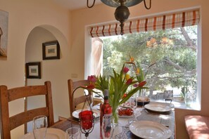 A dining table set with plates, glasses, and a vase with flowers.