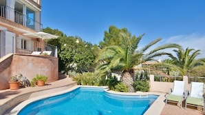 A swimming pool with a curved edge, surrounded by potted plants and palm trees. - Charming Villa with Sea Views & Pool (Andratx)