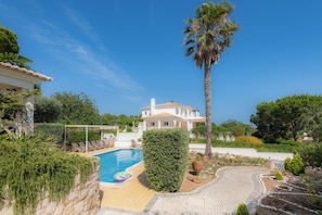 A villa with a swimming pool, surrounded by greenery and a clear sky. - Villa Ladeira - Private pool, Sea view, Smart tv, games, wifi, Ac (Albufeira)
