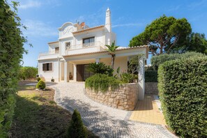 A two-story house with a stone pathway leading to the entrance, surrounded by greenery and a clear blue sky. - Villa Ladeira - Private pool, Sea view, Smart tv, games, wifi, Ac (Albufeira)