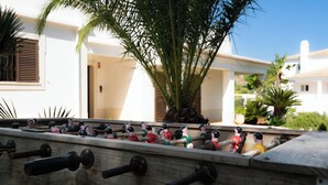 A foosball table with figurines, a palm tree, and a building with white walls and a tiled roof. - Villa Ladeira - Private pool, Sea view, Smart tv, games, wifi, Ac (Albufeira)