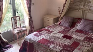 A bedroom with a large bed, a nightstand, a chair, and a window with curtains. - Delightful provencal style villa on a single level with pool and stunning views. (Tourrettes)