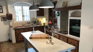 A kitchen with a central island, wooden cabinets, a built-in oven, and pendant lighting. - Delightful provencal style villa on a single level with pool and stunning views. (Tourrettes)