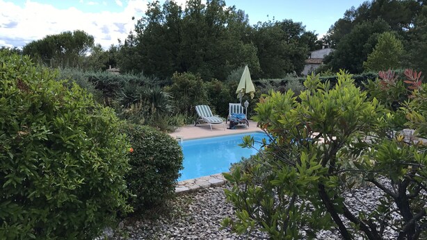 A swimming pool surrounded by greenery, with two lounge chairs and a small umbrella. - Delightful provencal style villa on a single level with pool and stunning views. (Tourrettes)