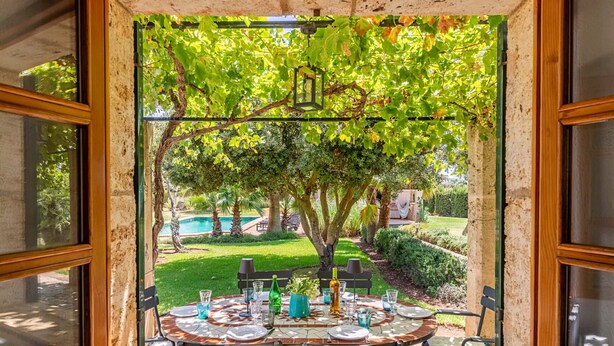 Un coin repas avec une table dressée pour quatre personnes, donnant sur un jardin.