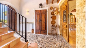 Un escalier menant à une pièce dotée d’un sol en pierre, de portes en bois et d’un intérieur rustique.