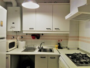 A kitchen with white cabinets, a microwave, a sink, and a stove. - Duplex apartment in Barrio de San Bernardo with parking (Sevilla)