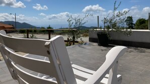 Eine weiße Bank auf einer Dachterrasse mit Blick auf Berge und einen klaren Himmel.