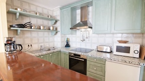Una cocina con gabinetes verdes, una encimera de madera, una cafetera, un tostador y un microondas.