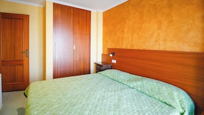 Un dormitorio con cama, armario de madera y mesita de noche.
