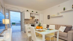 A modern kitchen with white cabinets, a dining area with a table and chairs, and a sofa. - House in front of the beach of Balestrate (Balestrate)