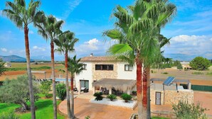 A modern house with a stone facade, a thatched-roof patio, and a view of the countryside. - Son Sastre 024 luxurious villa with large swimming pool, air conditioning, garden and terrace (Muro)