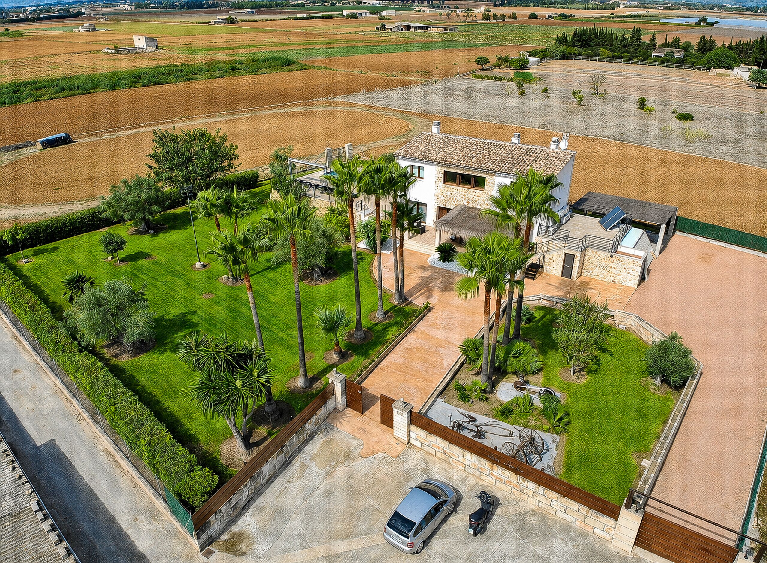 A large house with a spacious patio, surrounded by lush greenery and a well-maintained lawn.