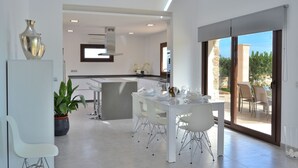 A modern kitchen with white cabinetry and a dining area with a white table and chairs. - Son Sastre 024 luxurious villa with large swimming pool, air conditioning, garden and terrace (Muro)